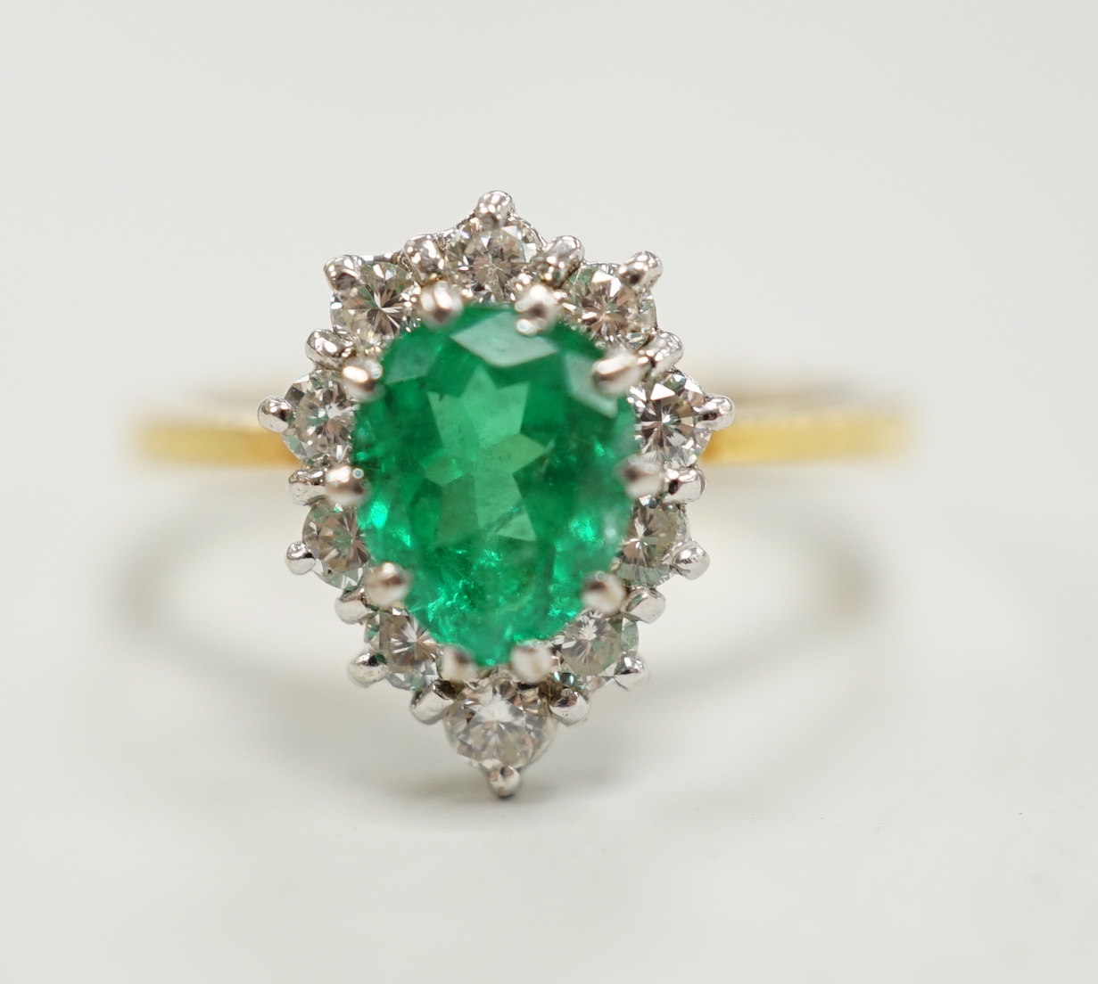 A modern 18ct gold, single stone emerald and diamond chip set pear shaped cluster ring, size M/N, gross weight 3.9 grams.